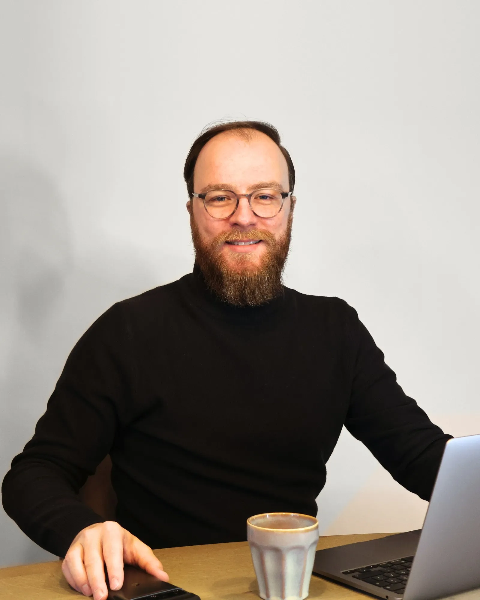 Sebastian Weidlich am Schreibtisch mit Laptop und Kaffeetasse
